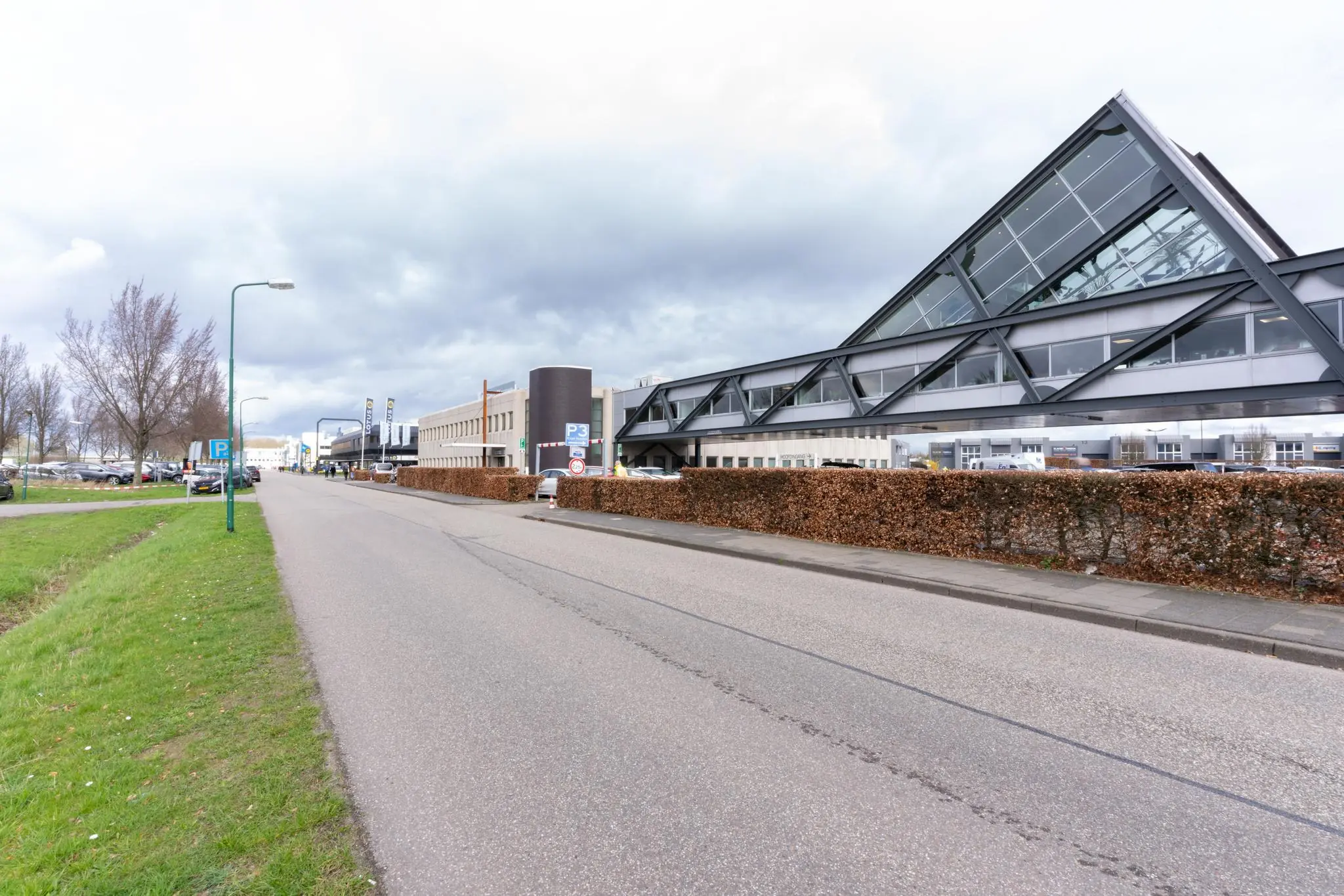 Bedrijfsgebouw aan de Meidoornkade met opvallend schuine glazen gevel langs een rustige straat.