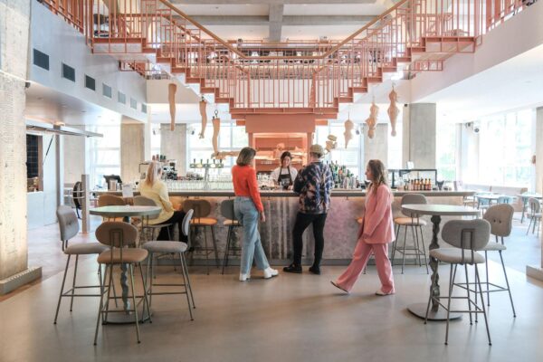 Modern café aan het Weesperplein met opvallend roze trapdesign en gasten aan de bar.