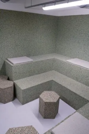 Moderne, hoekige zitruimte met terrazzo-banken en zeshoekige krukken op het Weesperplein.