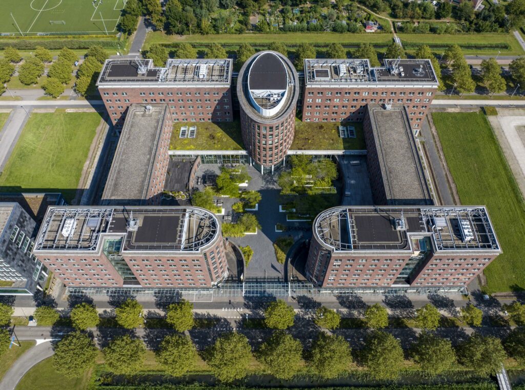 Luchtfoto van het kantoorgebouw aan de Orteliuslaan in Utrecht met een opvallende U-vormige structuur en groene daken.