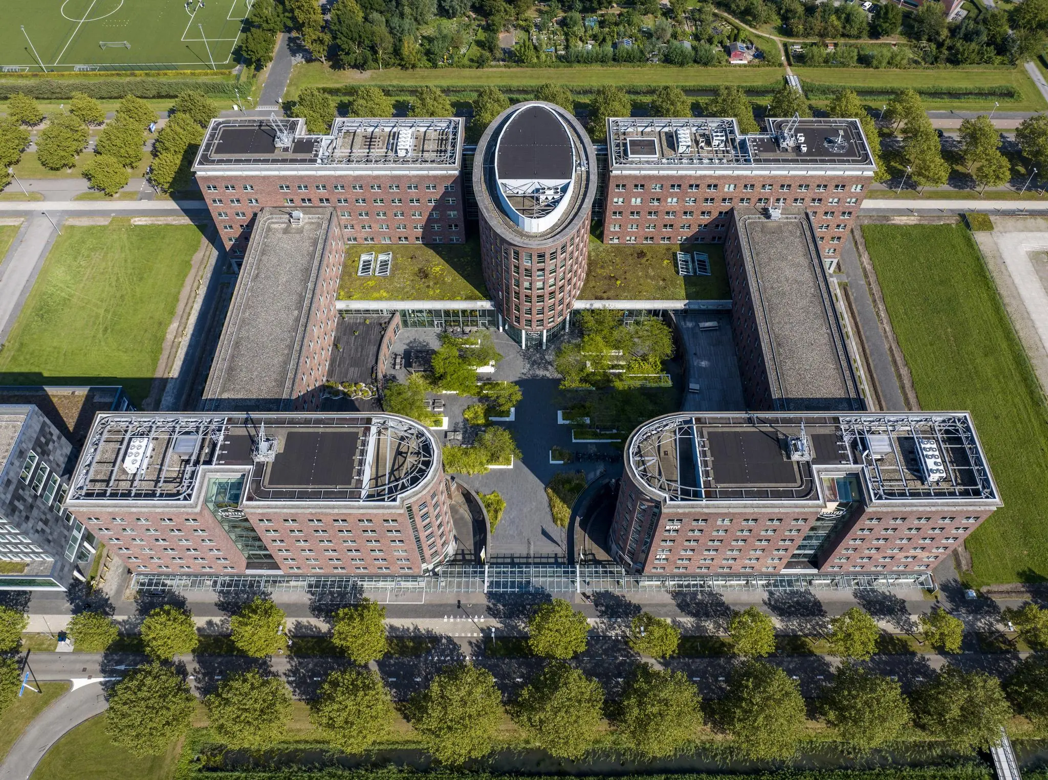 Luchtfoto van het kantoorgebouw aan de Orteliuslaan in Utrecht met een opvallende U-vormige structuur en groene daken.