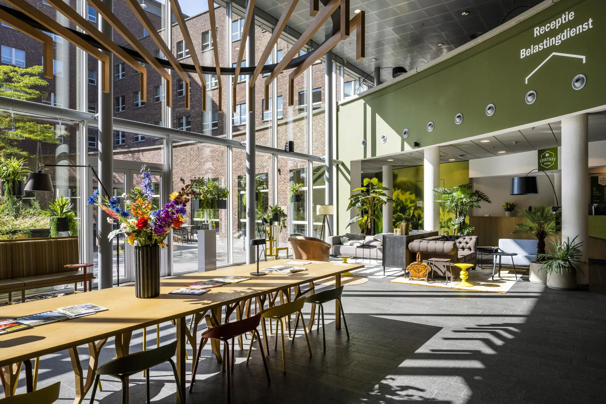 Moderne wachtruimte met veel daglicht, planten en zitgelegenheid in het belastingdienstkantoor aan de Orteliuslaan.