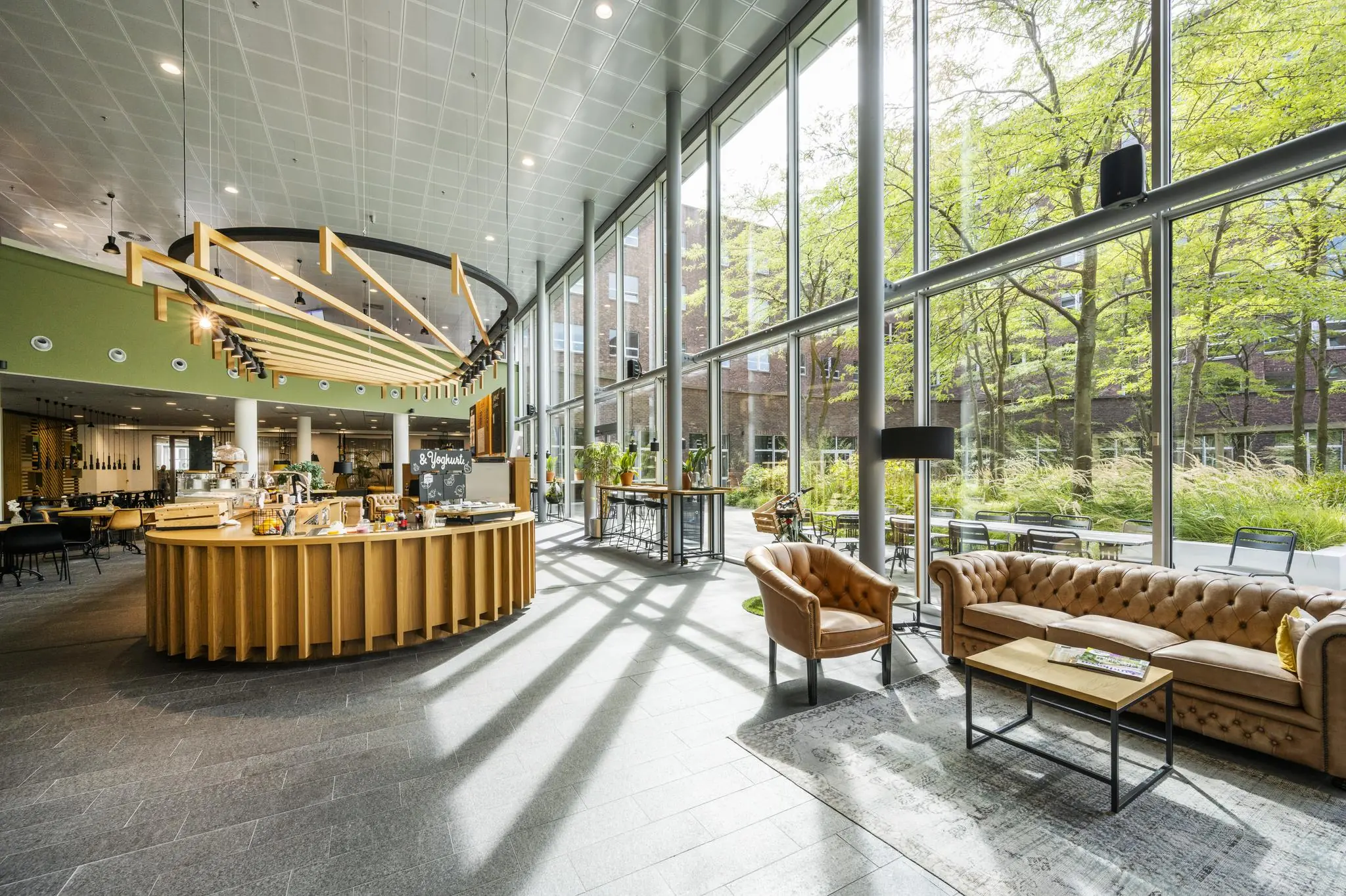 Lichte en moderne lobby met zithoek, koffiebar en grote ramen aan de Orteliuslaan.