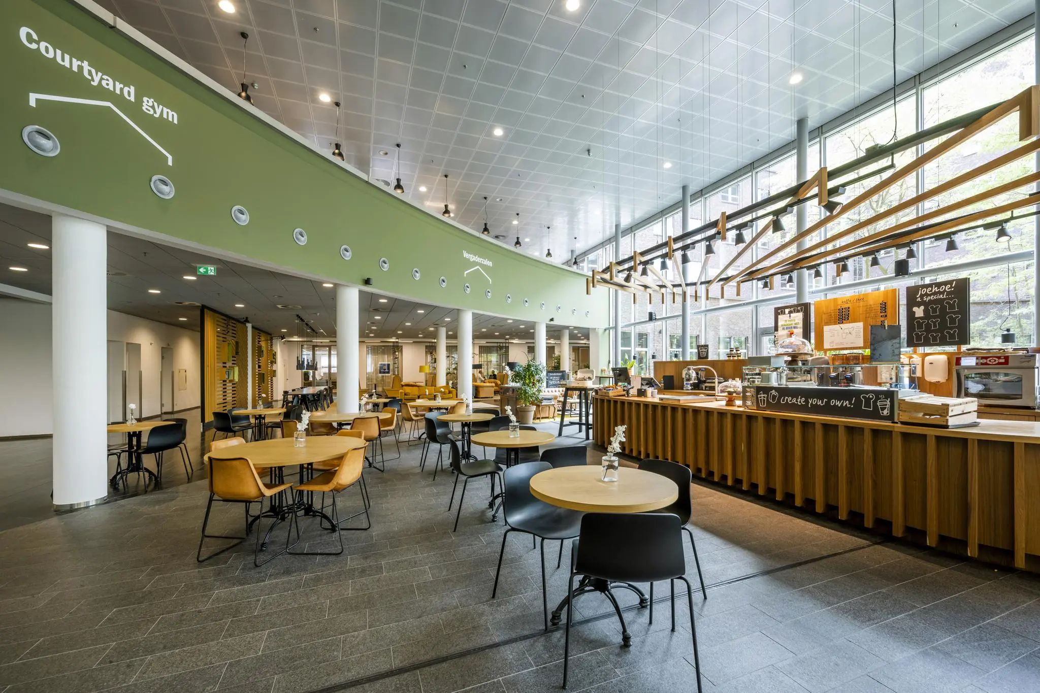 Moderne, lichte bedrijfskantine aan de Orteliuslaan met zitgedeelte en koffiebar.