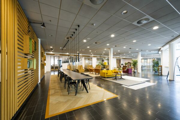 Moderne en ruim ingerichte kantoorlobby aan de Orteliuslaan met lange vergadertafel, loungehoek en veel natuurlijk licht.