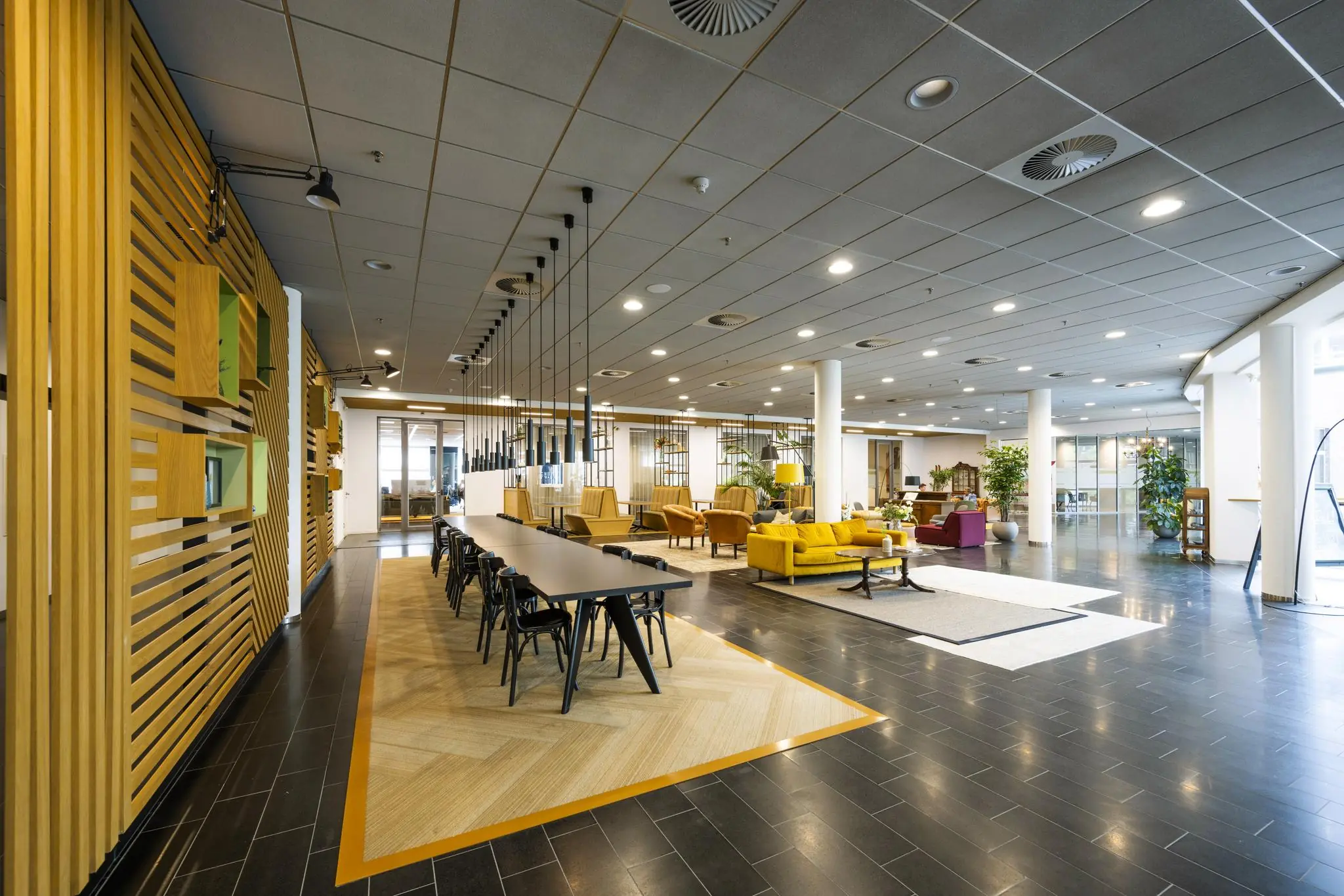 Moderne en ruim ingerichte kantoorlobby aan de Orteliuslaan met lange vergadertafel, loungehoek en veel natuurlijk licht.