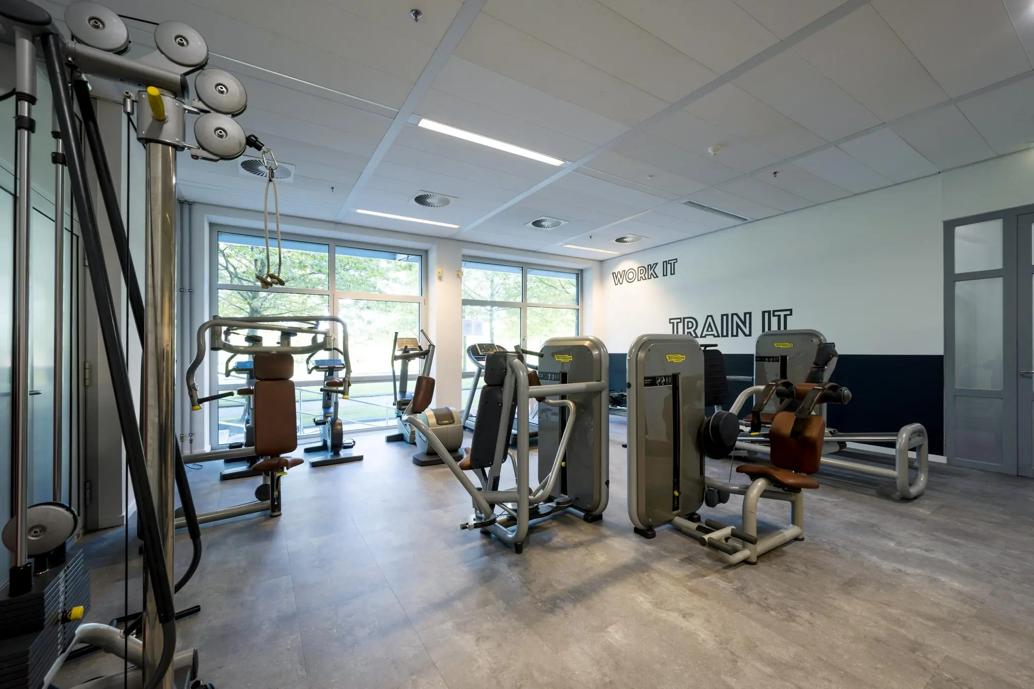 Moderne fitnessruimte aan de Orteliuslaan met diverse krachttrainingsapparaten en natuurlijk daglicht.