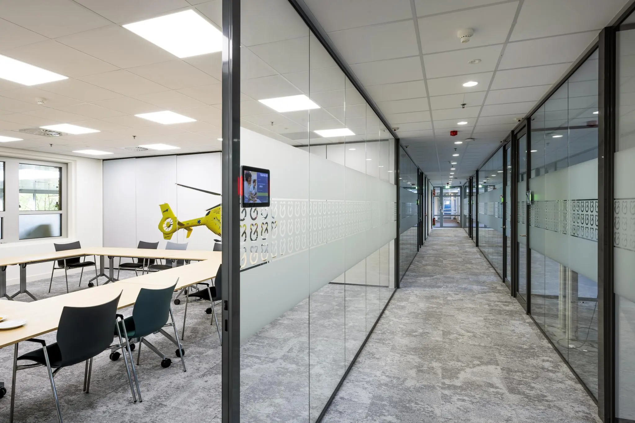 Modern kantoorinterieur met een glazen vergaderruimte aan de Orteliuslaan en een lange gang met kantoren.