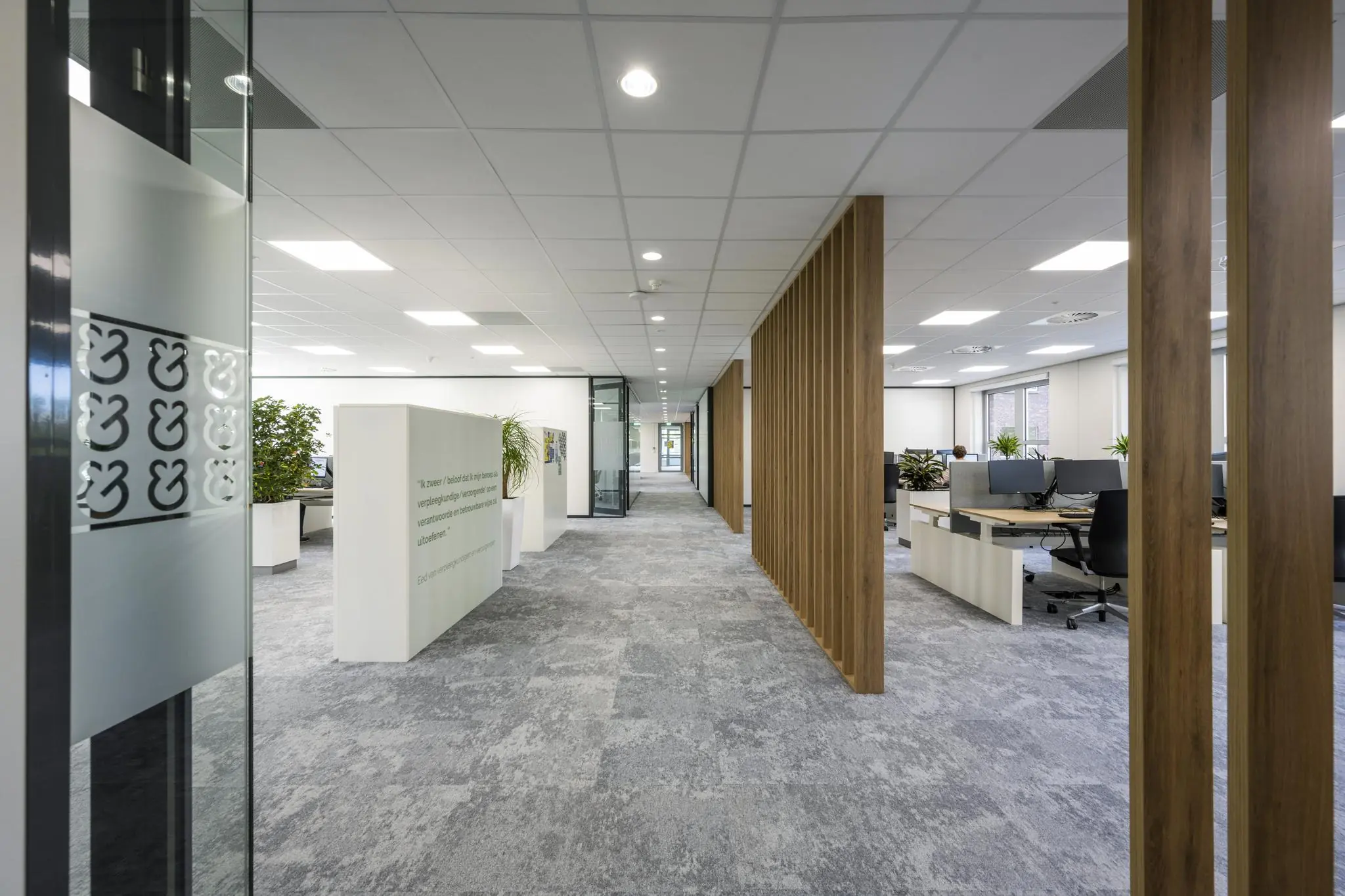 Moderne kantoorruimte aan de Orteliuslaan met open werkplekken, glazen wanden en houten scheidingspanelen.