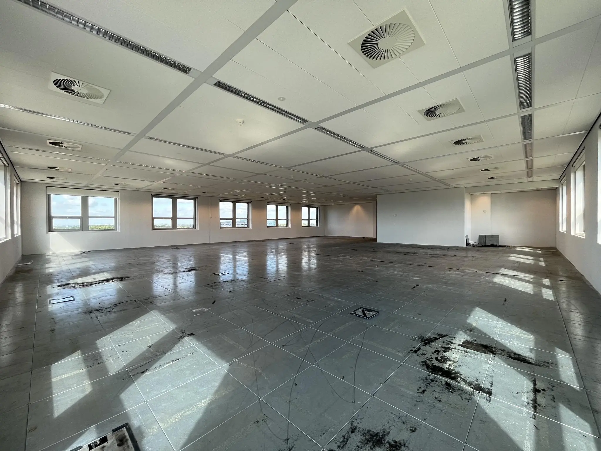 Leeg kantoorpand aan de Orteliuslaan met systeemplafond, tegelvloer en grote ramen.