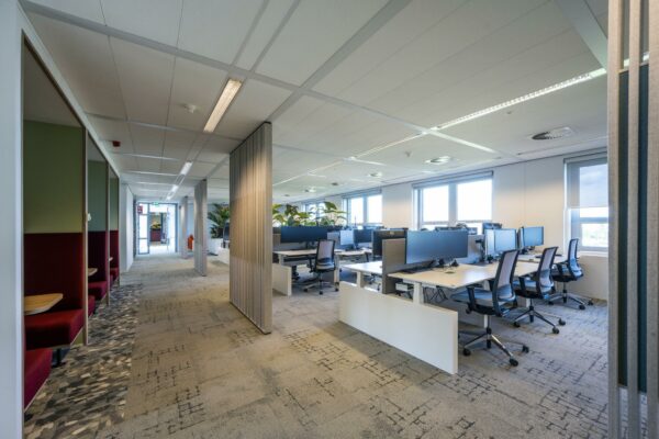 Modern kantoorinterieur aan de Orteliuslaan met open werkplekken, bureaustoelen en semi-afgesloten vergelhoekjes.