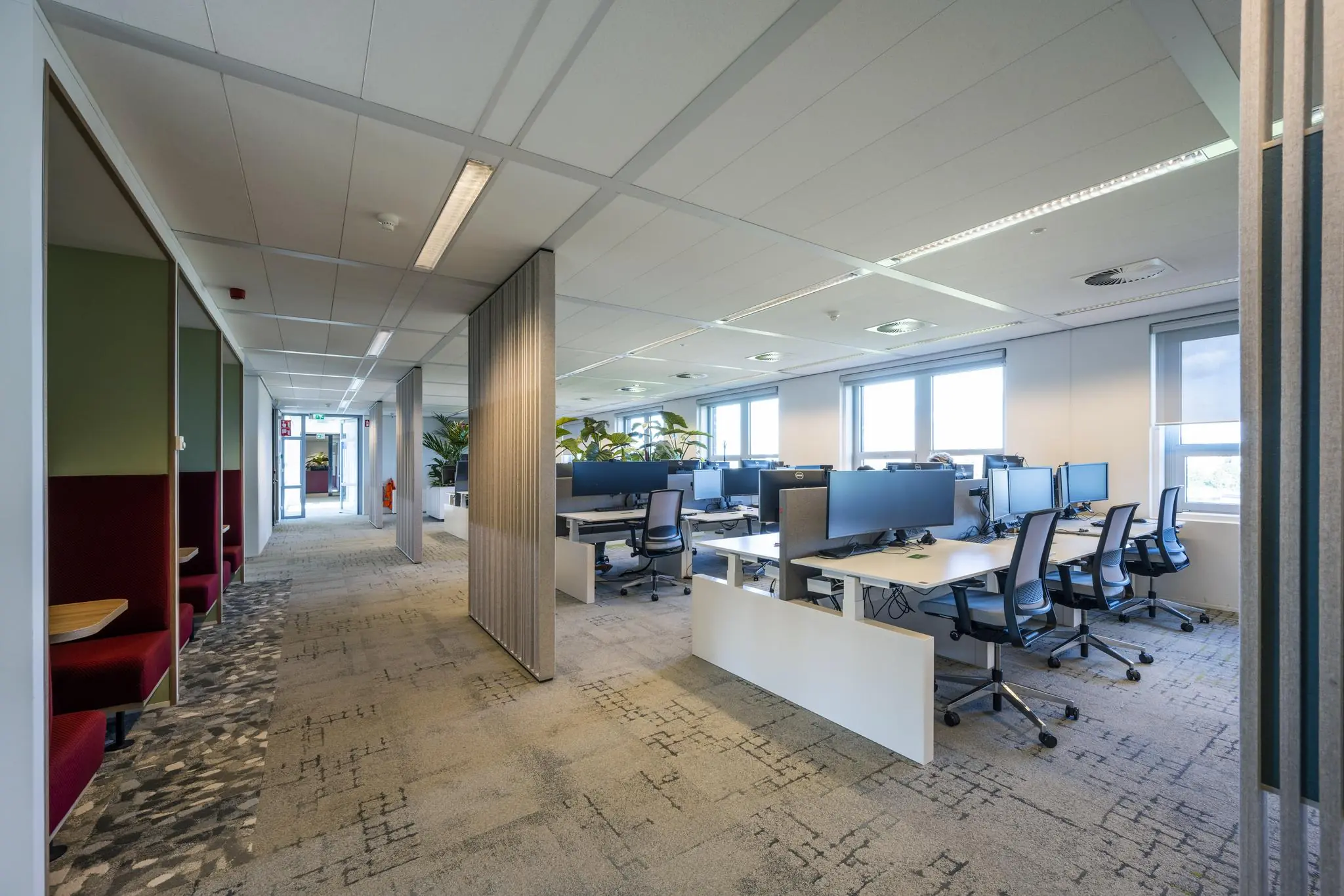 Modern kantoorinterieur aan de Orteliuslaan met open werkplekken, bureaustoelen en semi-afgesloten vergelhoekjes.