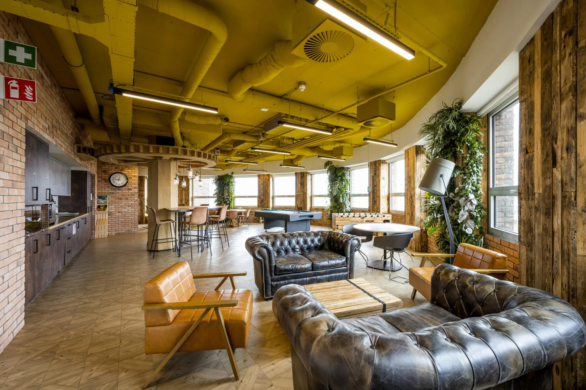 Moderne lounge- en recreatieruimte op de Orteliuslaan met leren banken, een tafelvoetbalspel en groene accenten.