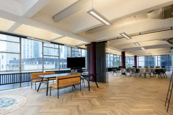 Moderne, open kantoorruimte aan de Vlasmarkt met houten vloer, grote ramen en diverse zitplekken.