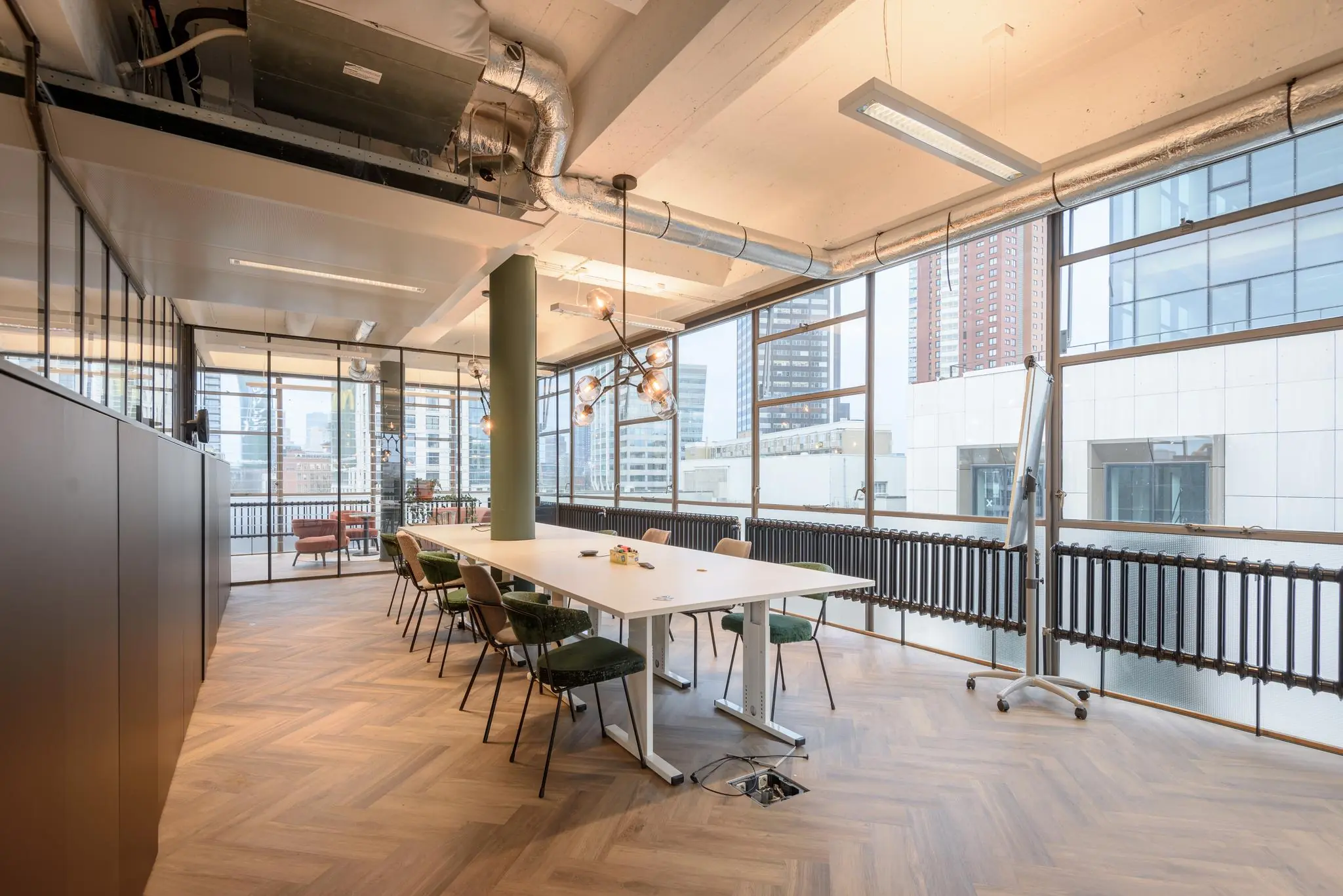 Moderne vergaderruimte op de Vlasmarkt met grote ramen, industrieel plafond en houten visgraatvloer.