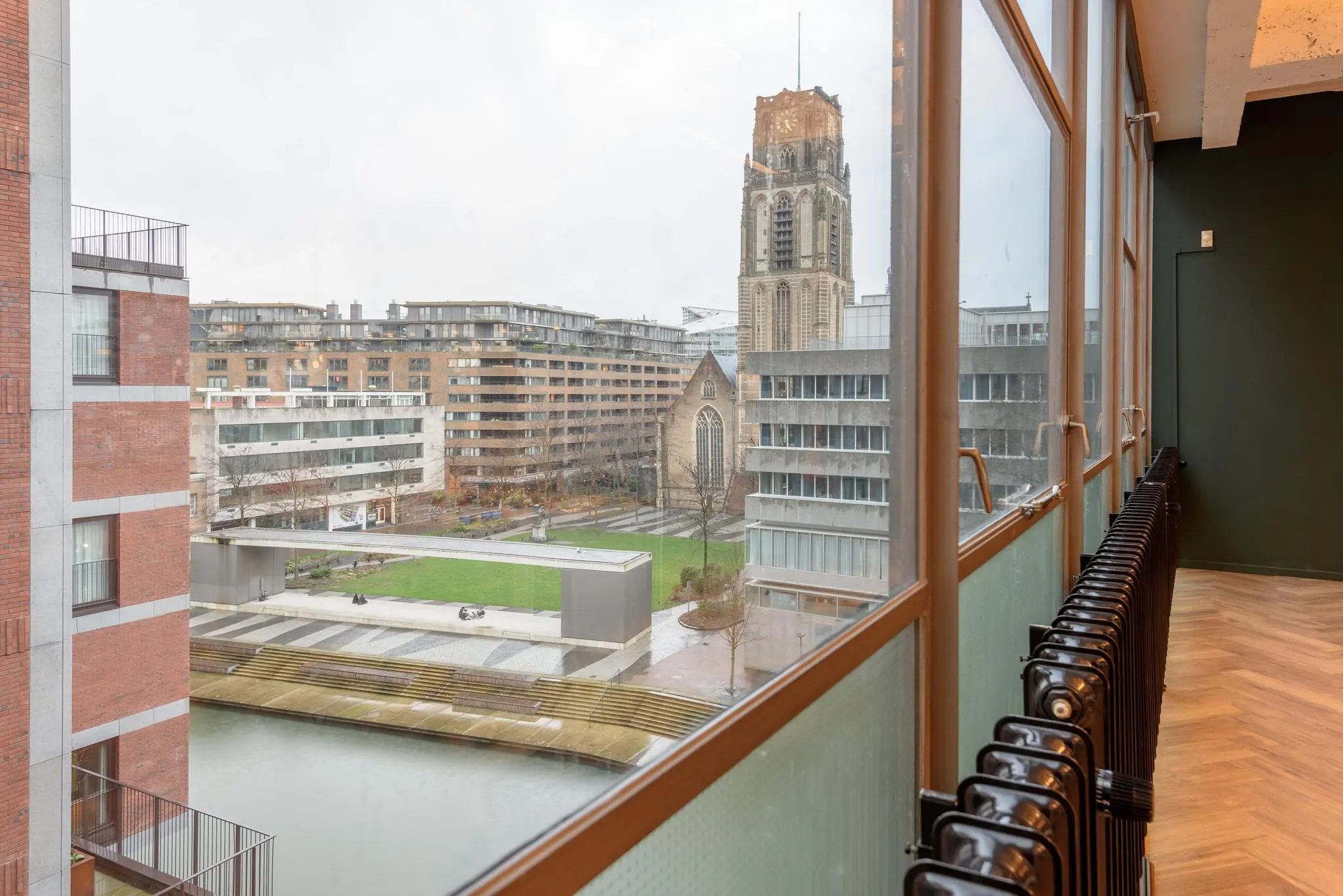 Uitzicht vanuit een modern gebouw op de Vlasmarkt in Rotterdam met de Laurenskerk op de achtergrond.