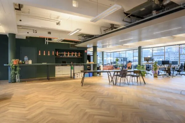 Moderne en ruime kantoorruimte aan de Vlasmarkt met open werkplekken, een lange koffietafel en veel natuurlijk licht.