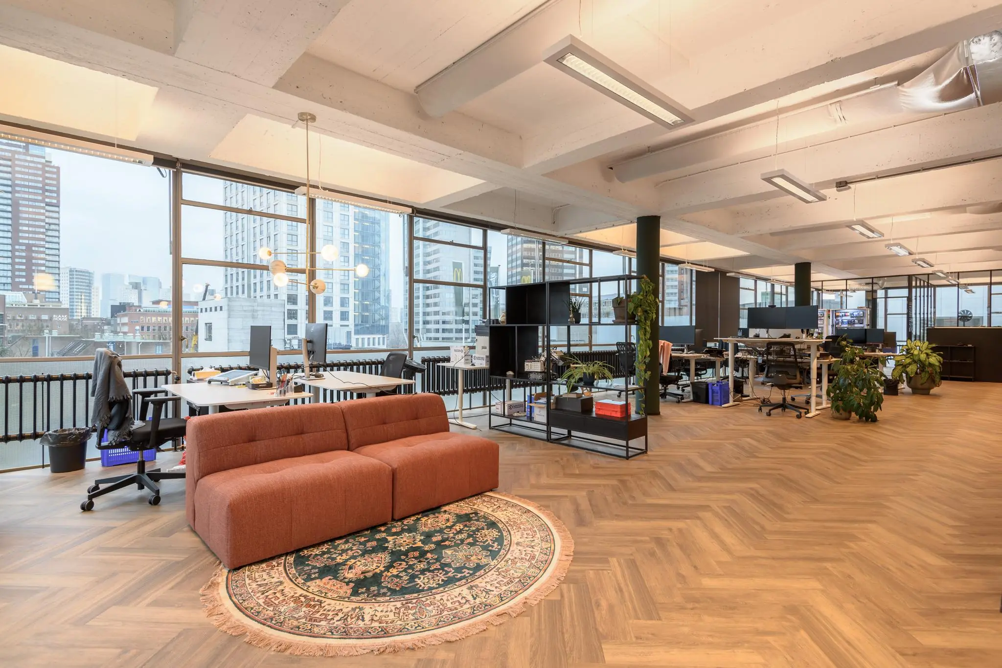 Modern kantoorinterieur aan de Vlasmarkt met grote ramen, open werkplekken en een zithoek met vloerkleed.
