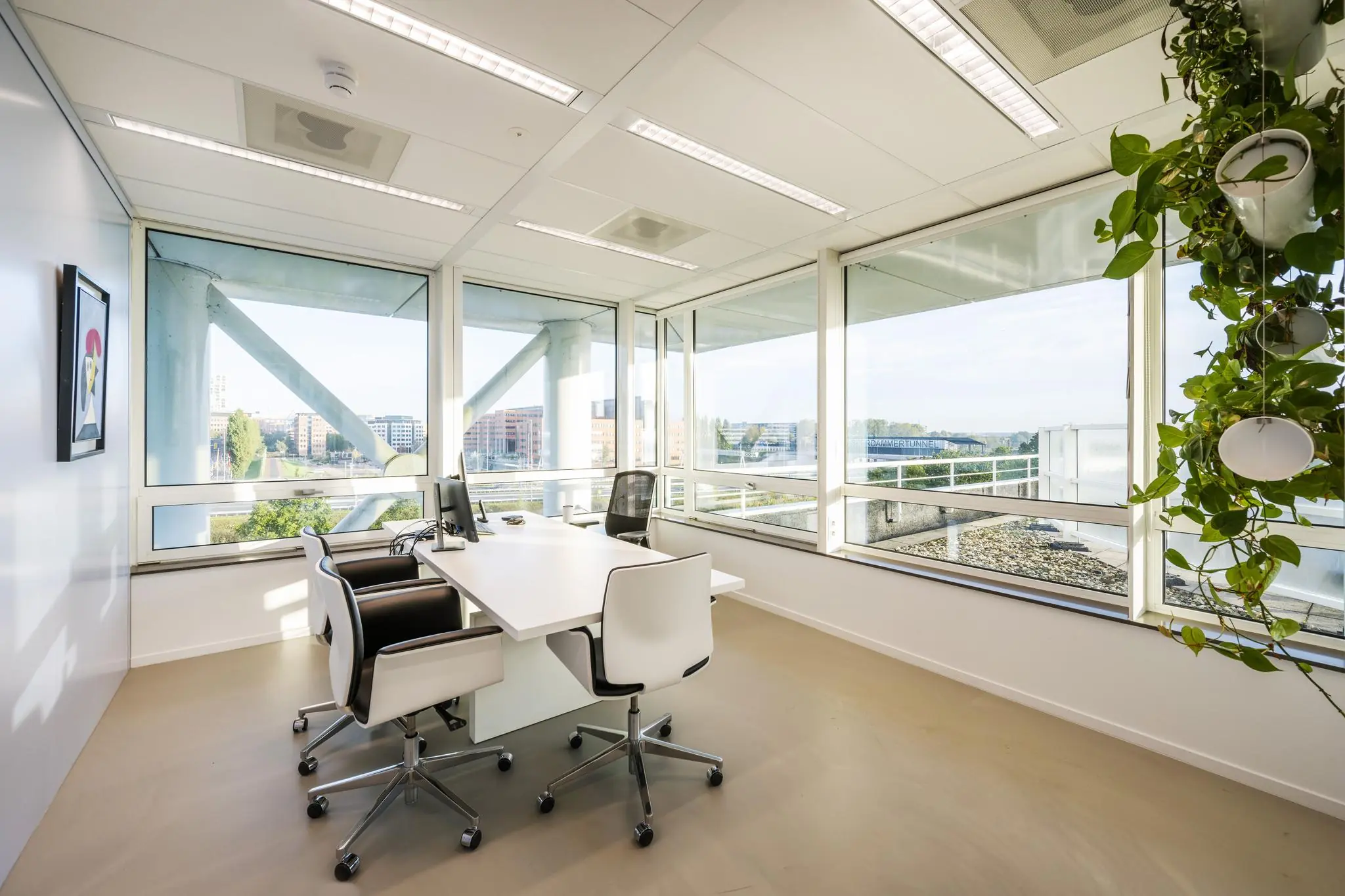 Modern kantoor met grote ramen, witte meubels en uitzicht op bedrijventerrein aan de Paalbergweg.