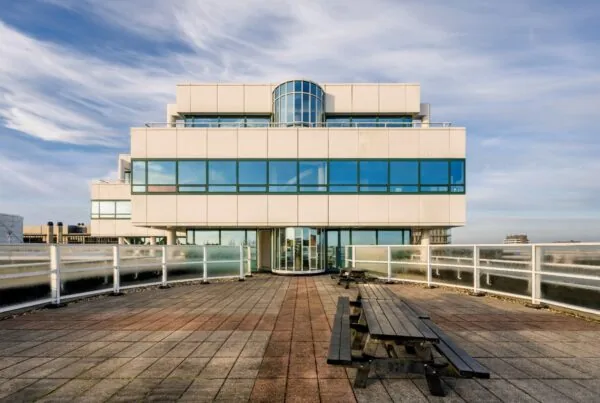 Modern kantoorgebouw aan de Paalbergweg met dakterras en picknickbanken.