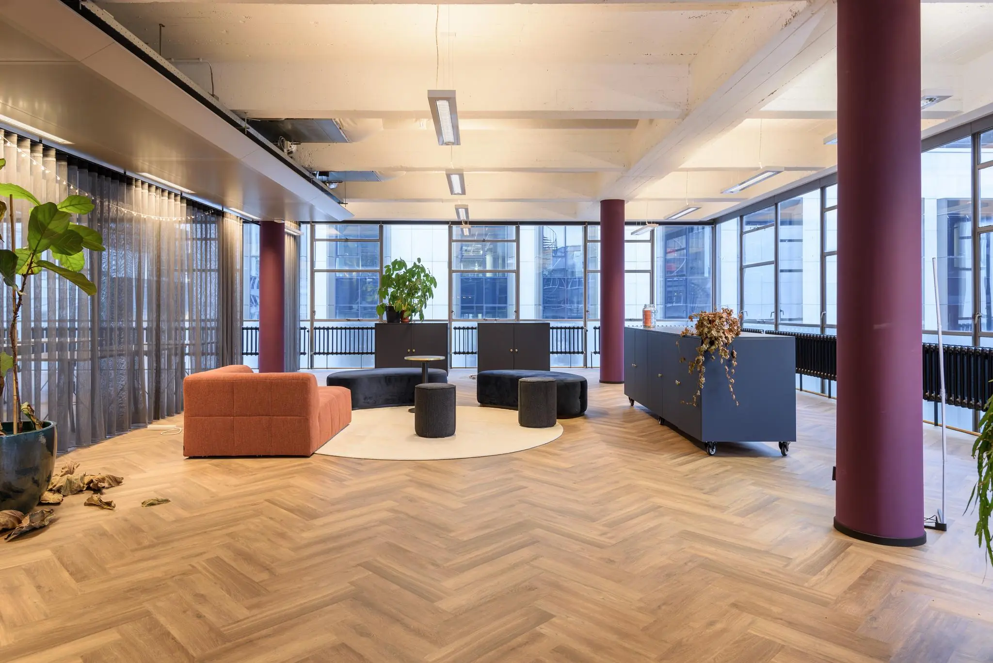 Modern ingerichte kantoorruimte aan de Vlasmarkt met houten visgraatvloer, kleurrijke meubels en grote ramen.