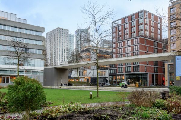 Moderne gebouwen en een verhoogd wandelpad aan de Vlasmarkt in een groen stadspark.