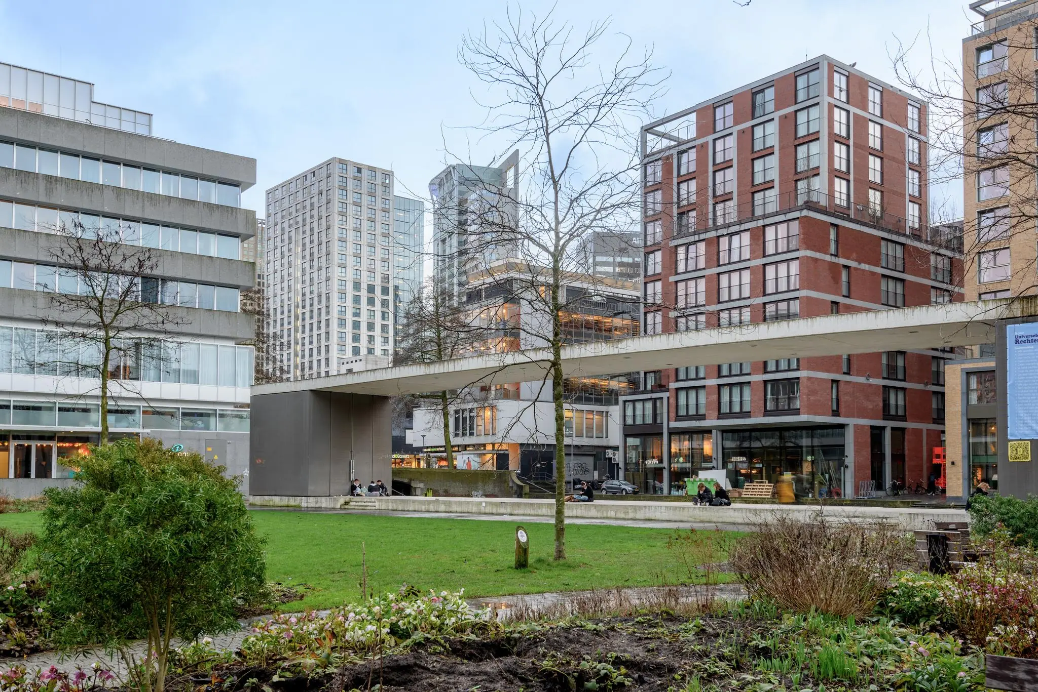 Moderne gebouwen en een verhoogd wandelpad aan de Vlasmarkt in een groen stadspark.