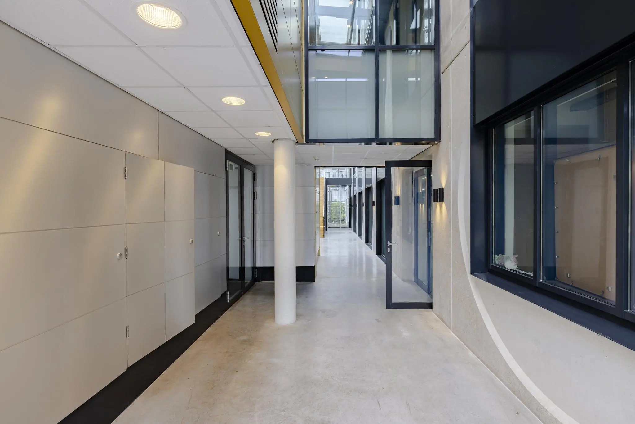 Moderne gang met glazen deuren en ramen in een kantoorpand aan de Laarderhoogtweg.