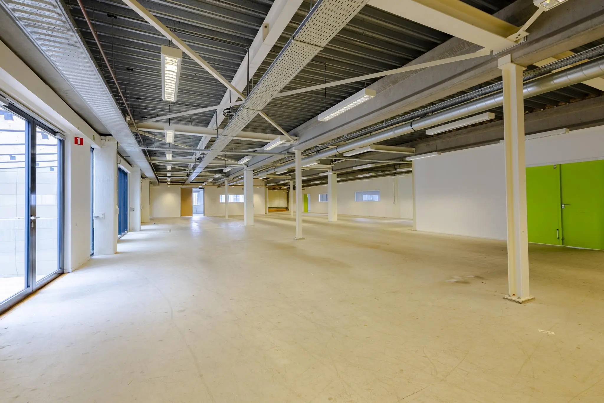 Leeg bedrijfspand aan de Laarderhoogtweg met industriële afwerking en groene deuren.