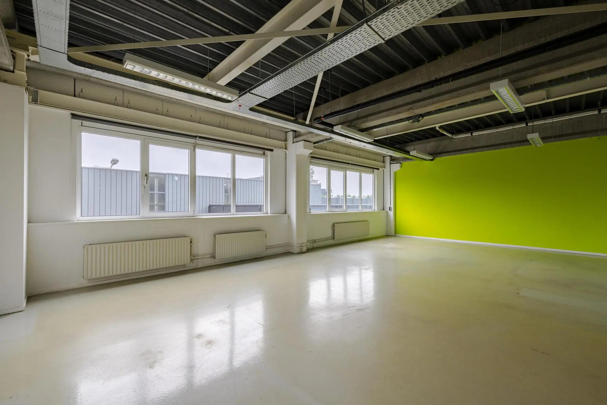 Leeg kantoorpand aan de Laarderhoogtweg met opvallende groene muur en zicht op industriële buitenzijde.