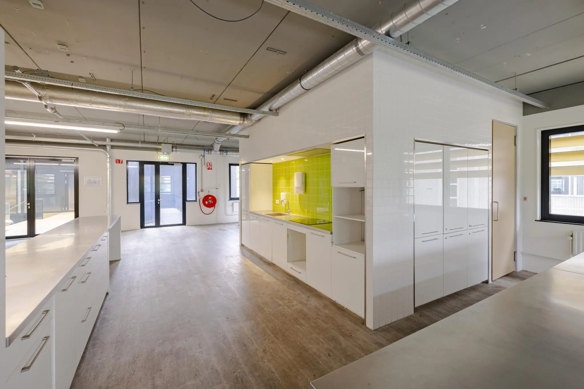 Moderne, industriële keukenruimte met witte kasten en een felgroene achterwand aan de Laarderhoogtweg.