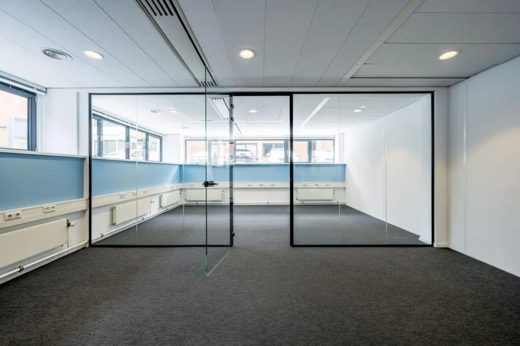 Modern kantoorinterieur met glazen vergaderruimte, blauwe lambrisering en grijze vloerbedekking aan de Stroombaan.