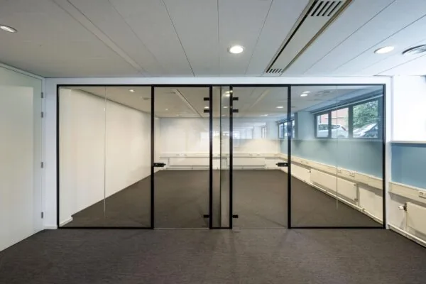 Kantoorruimte met glazen wanden en zwarte kozijnen in een modern bedrijfsgebouw aan de Stroombaan.