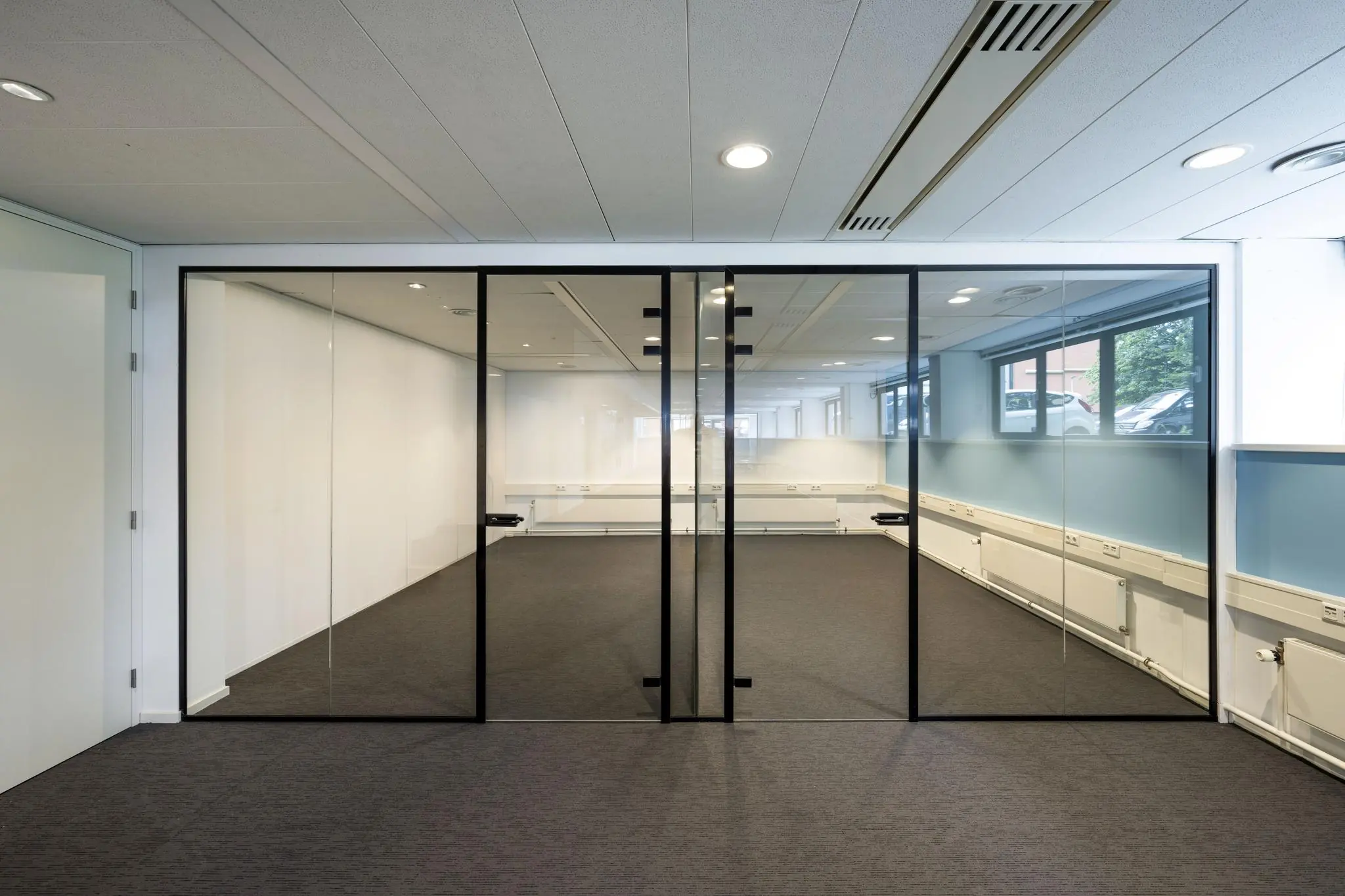Kantoorruimte met glazen wanden en zwarte kozijnen in een modern bedrijfsgebouw aan de Stroombaan.
