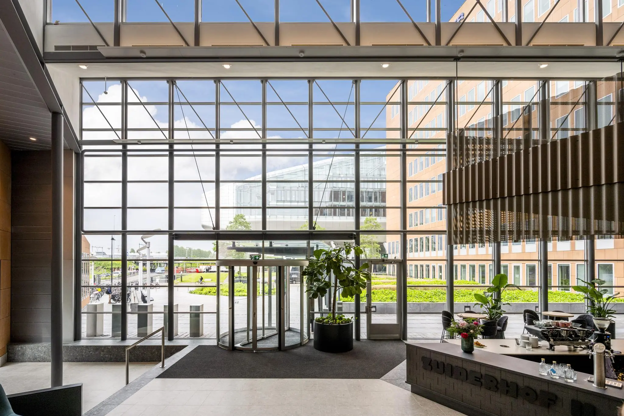 Inkomhal van een modern kantoorpand aan de Jachthavenweg met glazen gevel, draaideur en koffiebar.