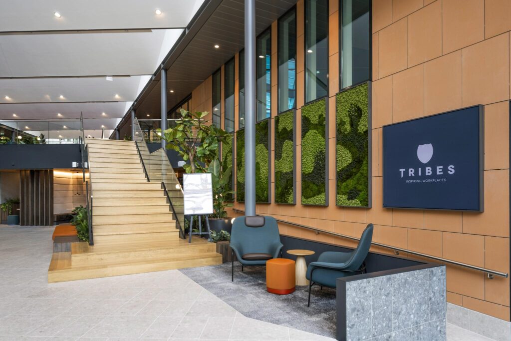 Moderne kantoorlobby aan de Jachthavenweg met houten trap, groene plantenwand en Tribes-logo.