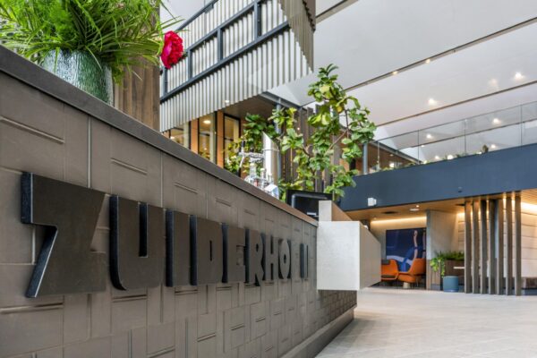 Moderne hotellobby van het Zuiderhof aan de Jachthavenweg met strakke inrichting, planten en een balie met logo.