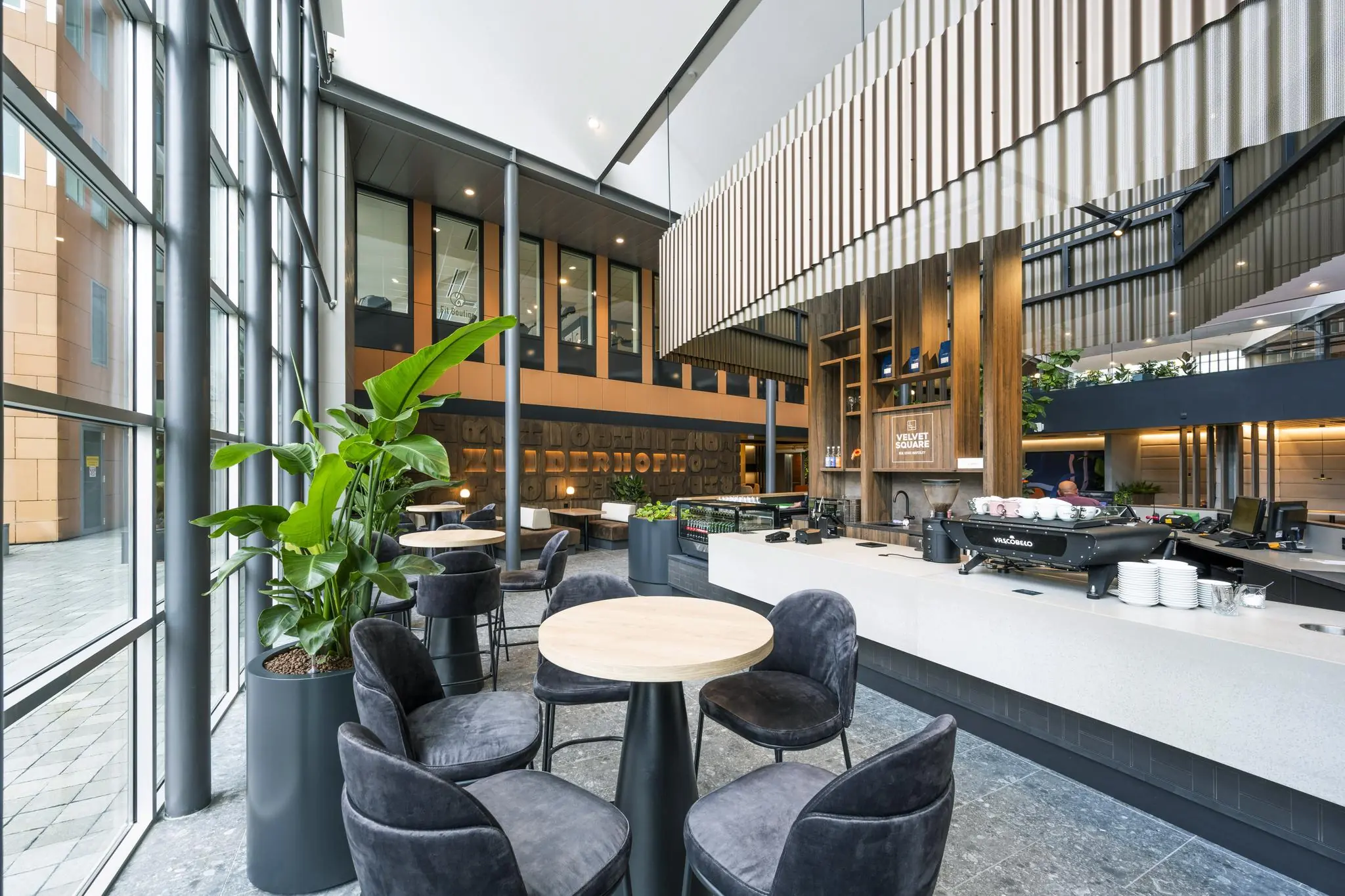 Moderne koffiebar met zitgelegenheid en grote raampartijen in een bedrijfsgebouw aan de Jachthavenweg.