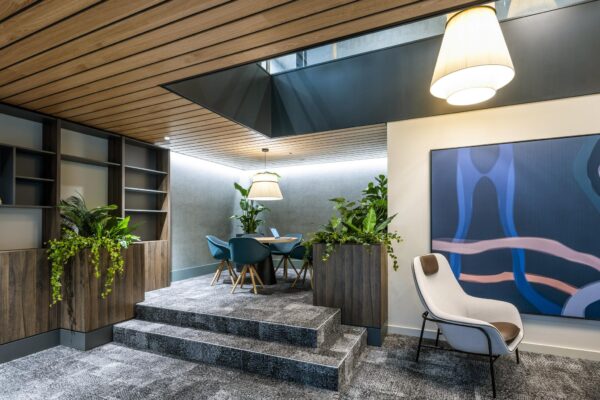 Moderne zithoek aan de Jachthavenweg met comfortabele stoelen, grote plantenbakken en abstracte kunst aan de muur.