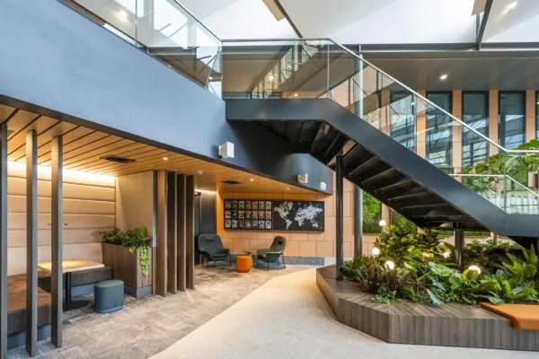 Moderne, lichtovergoten kantoorruimte aan de Jachthavenweg met een zwarte trap, groene plantenwand en zitgedeelte.