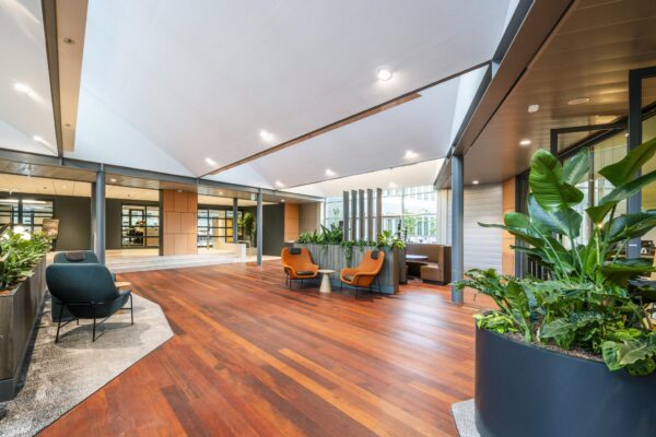 Moderne kantoorlobby aan de Jachthavenweg met houten vloer, stijlvolle zitplekken en veel groen.