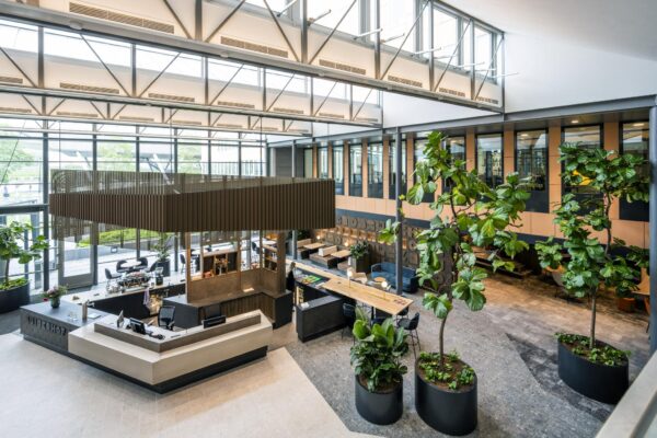 Moderne en lichte kantoorlobby aan de Jachthavenweg met een receptiebalie, zitgedeelte en grote planten.