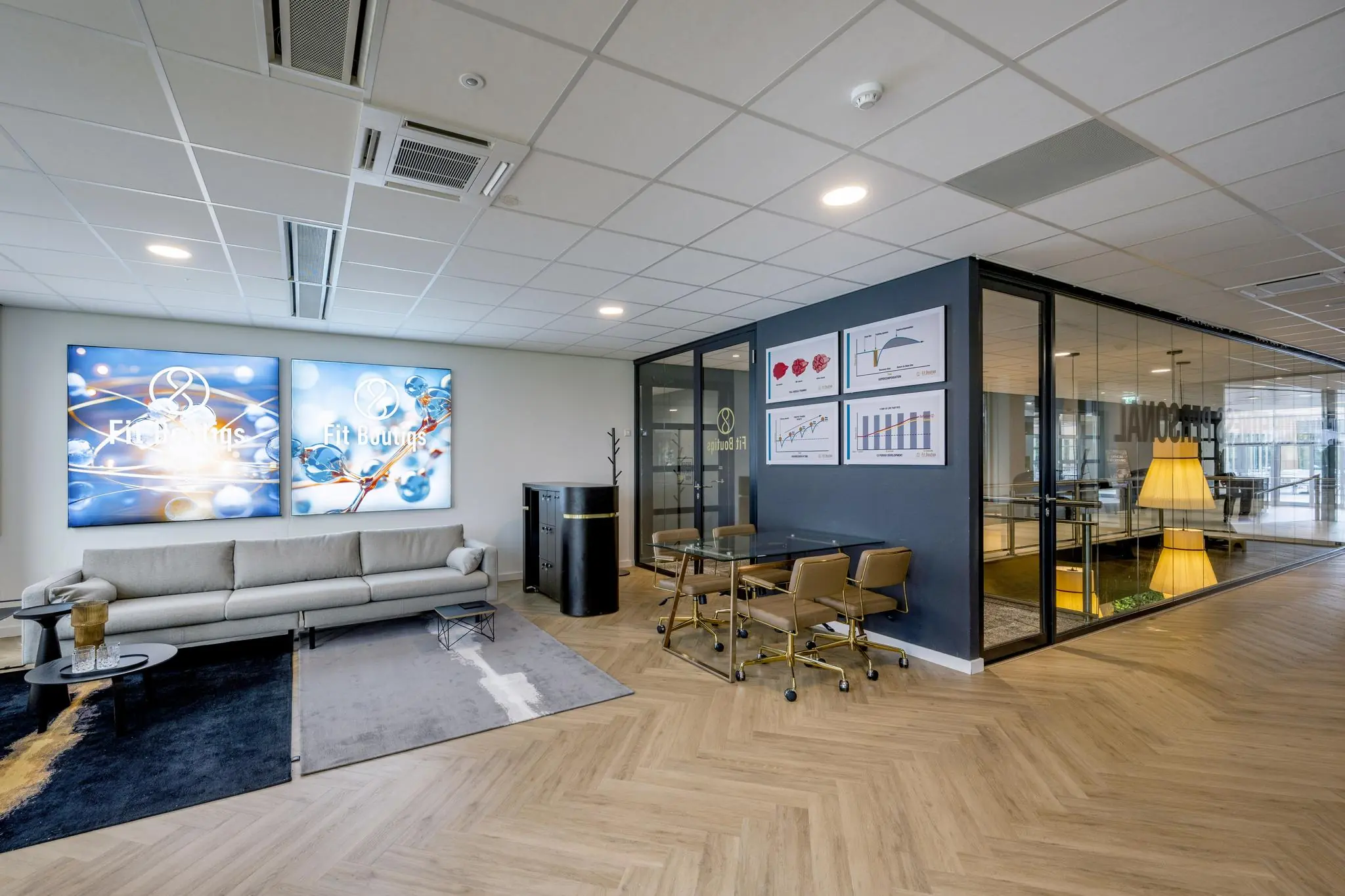 Moderne kantoorruimte van Fit Boutiqs met een zithoek, vergadertafel en glazen vergaderruimte.