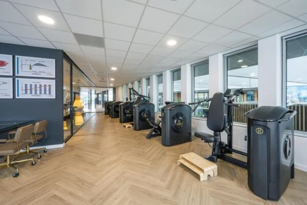 Moderne fitnessruimte aan de Jachthavenweg met geavanceerde krachttrainingsapparatuur langs een glazen wand.