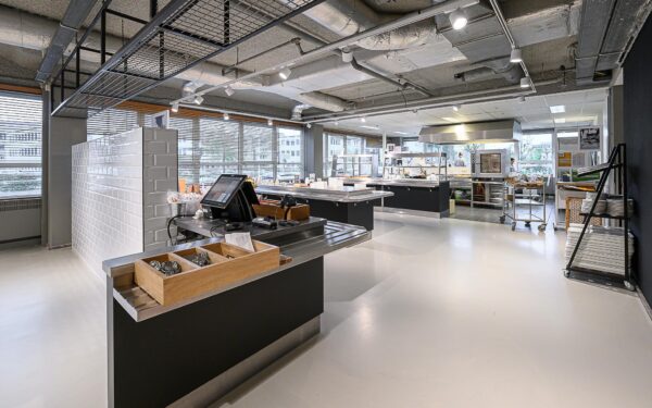 Moderne, open bedrijfskeuken aan de Rivium Westlaan met strakke werkstations en industriële afwerking.