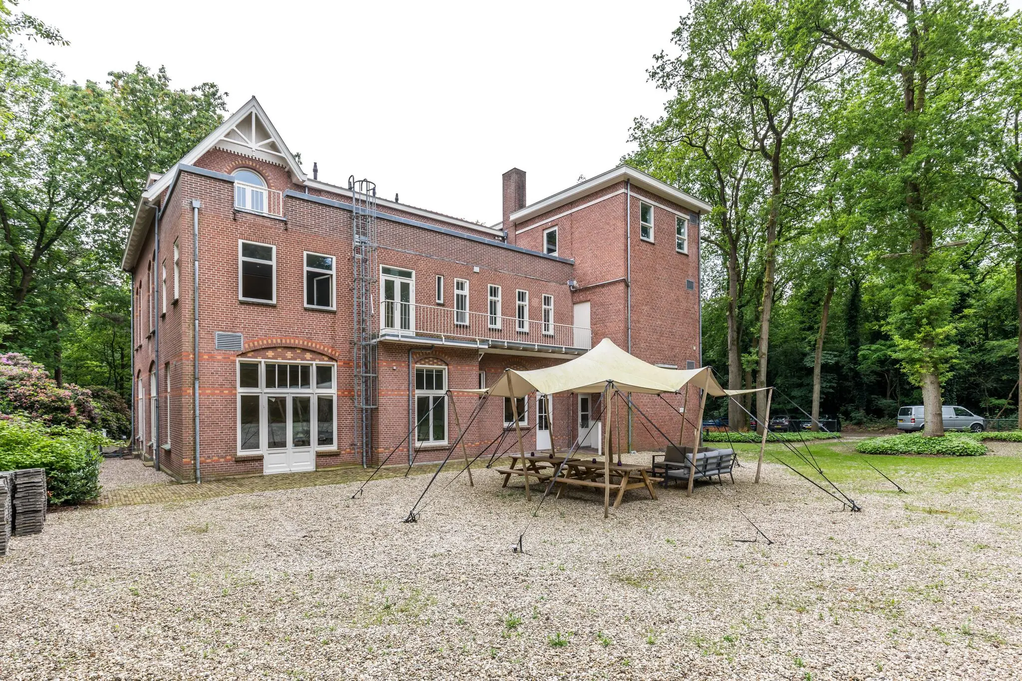 Historisch bakstenen pand aan de Amersfoortsestraat met een overdekte zitplek in een bosrijke tuin.