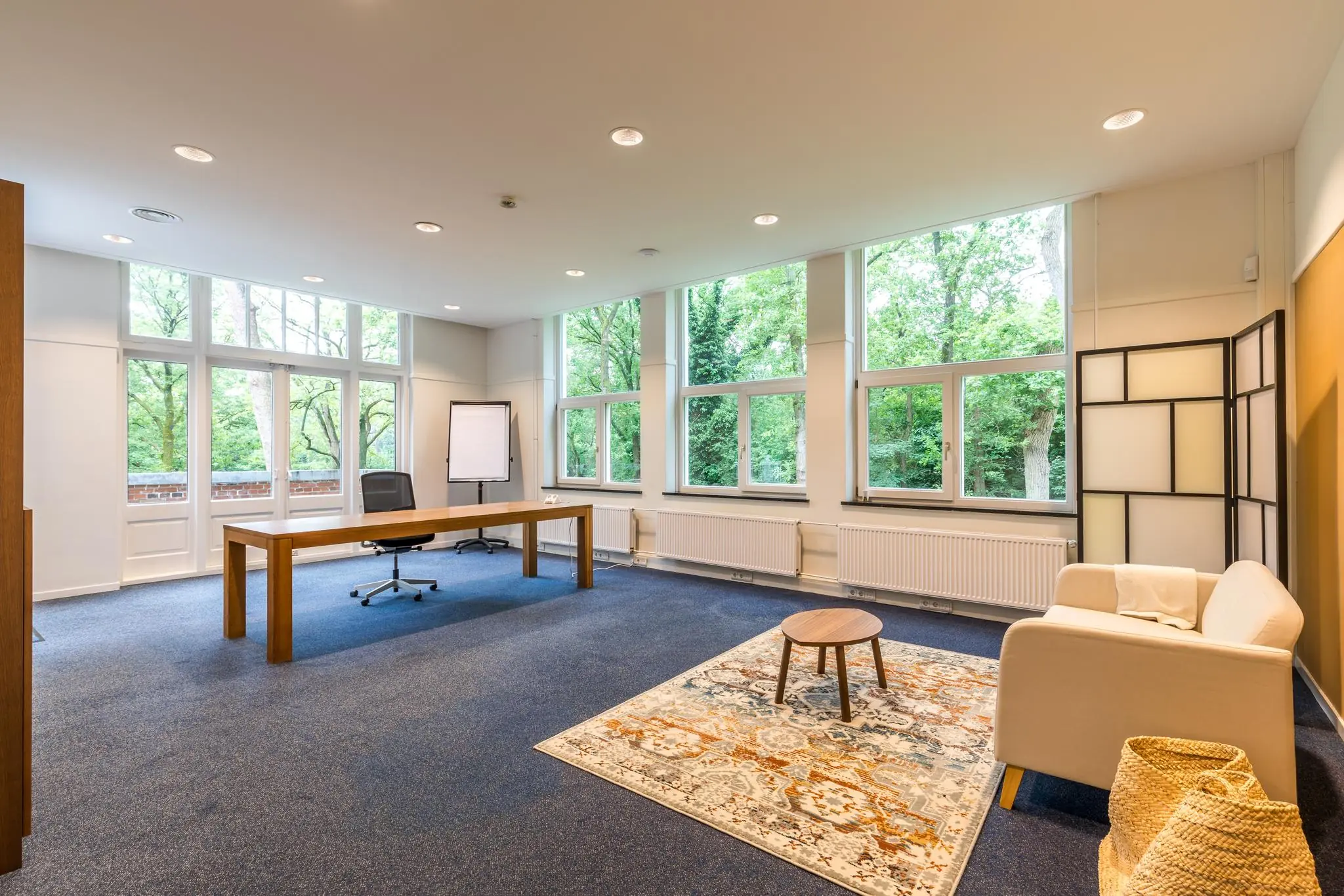 Licht en modern kantoor met groot bureau, zithoek en uitzicht op groene bomen aan de Amersfoortsestraat.