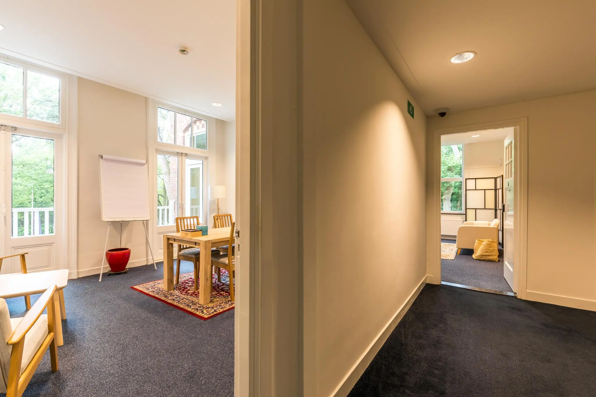 Doorkijk naar twee lichte kamers aan de Amersfoortsestraat, ingericht als vergaderruimte en loungehoek.