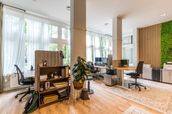 Modern ingerichte kantoorruimte aan de Amersfoortsestraat met werkplekken, grote ramen en een groene moswand.