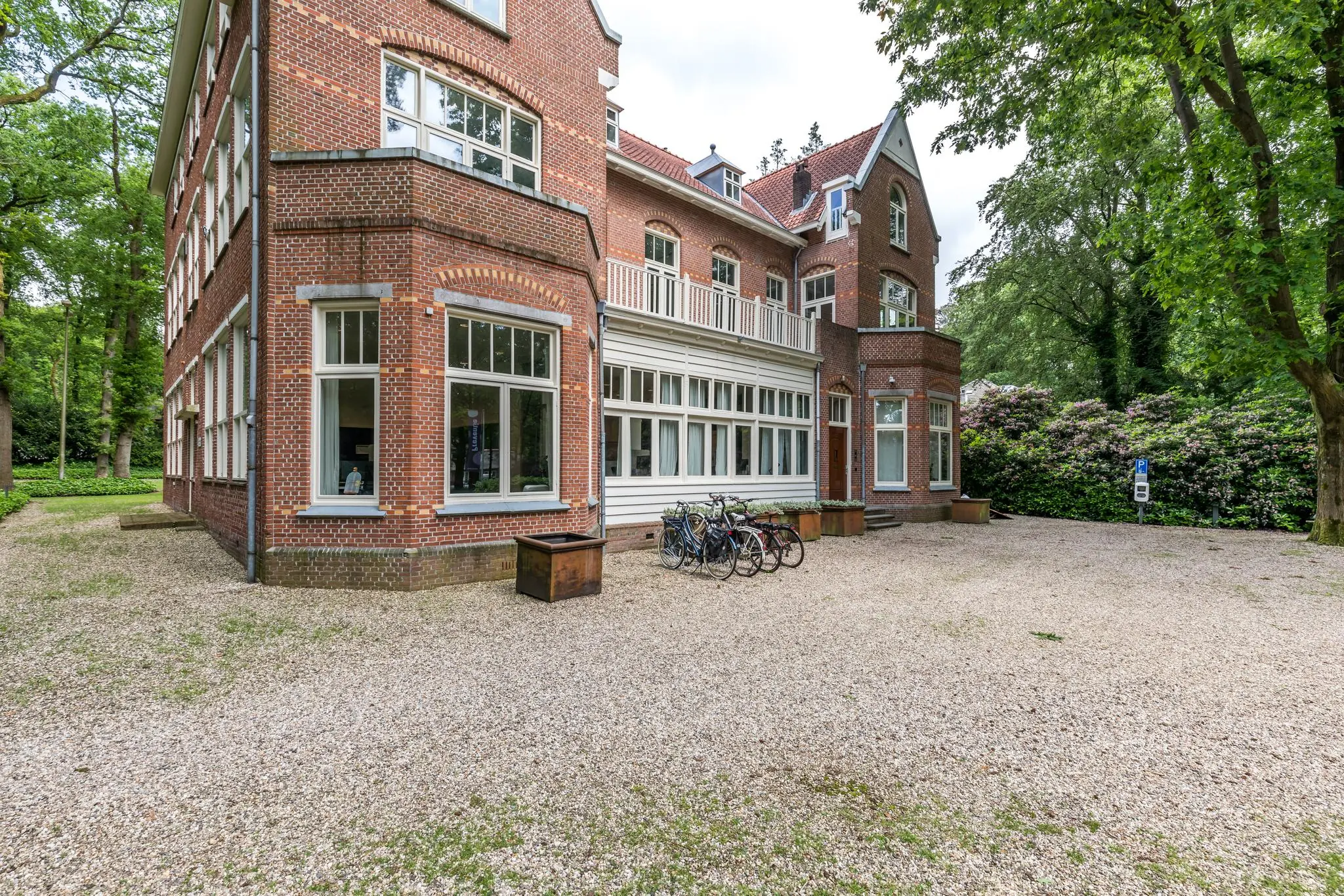 Groot bakstenen herenhuis aan de Amersfoortsestraat met fietsenrek en grindoprit, omringd door groen.
